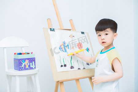 幼儿教育摄影照片_画画晚上孩子室内拿笔画画摄影图配图