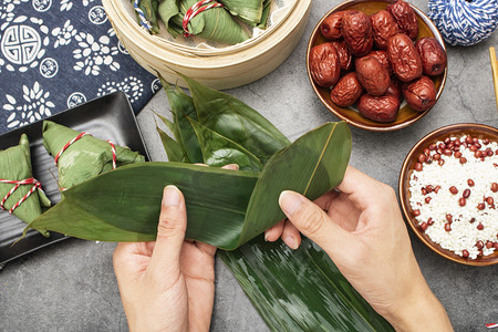 端午佳节摄影照片_传统节日白天裹粽子室内美食摆拍摄影图配图