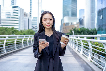 商务人像白天职场女性写字楼手拿咖啡和手机摄影图配图