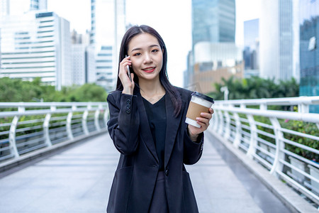 商务人像白天职场女性写字楼手拿咖啡打电话摄影图配图