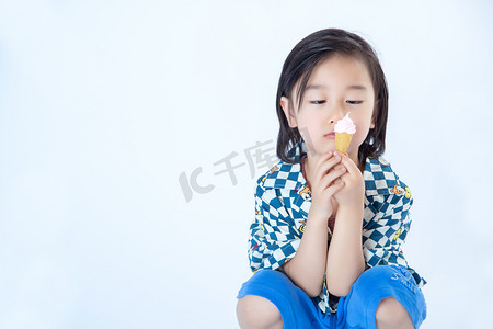 夏日儿童白天蹲着的男孩室内白背景手拿冰淇淋摄影图配图