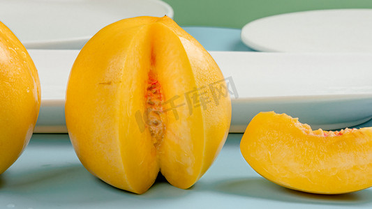 黄桃罐头卡通摄影照片_夏天多汁的水果白天新鲜黄桃室内切开果肉摄影图配图