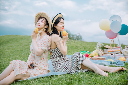 野餐郊游白天穿着裙子的两位美女草地抬头看天摄影图配图