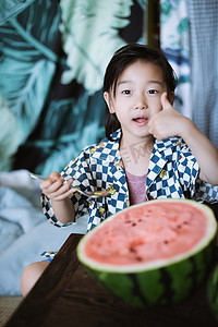 夏日儿童白天长发小男孩室内吃西瓜点赞摄影图配图
