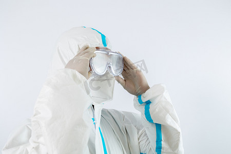中国医师节摄影照片_疫情防疫医生棚拍穿着防护服整理护目镜摄影图配图