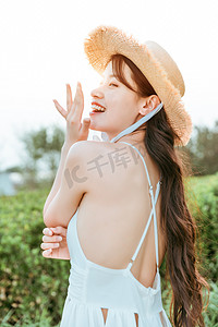 文艺夏天白天穿着白色长裙的美女户外捂嘴巴笑摄影图配图