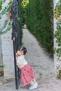 清新格子摄影照片_调皮女孩圣诞节女童花园站着靠门摄影图配图