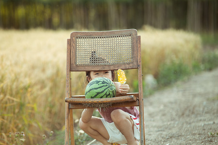 夏日麦田人像白天可爱的孩子麦田林间小路抱西瓜吃冰棍摄影图配图