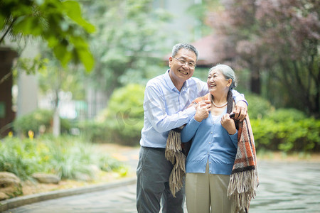 老中医给老人号脉摄影照片_老年生活白天一对老夫妻户外披上外衣摄影图配图