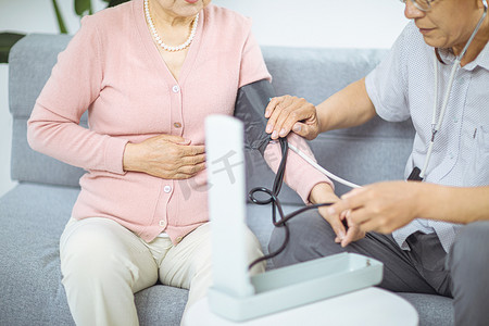 注重养生摄影照片_医疗养生白天两位老人室内量血压摄影图配图