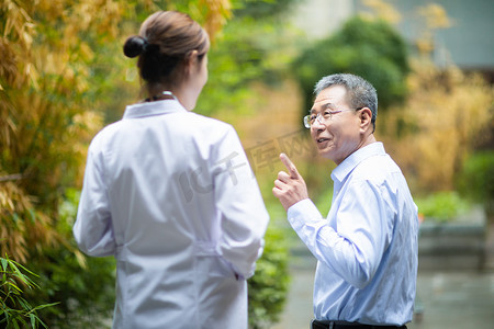 老人健康摄影照片_老年生活健康白天老人和医生户外走路交流摄影图配图