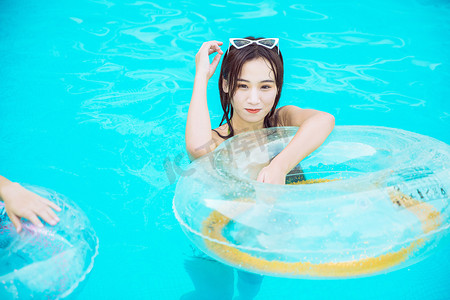 夏日清凉白天比基尼美女泳池抱着游泳圈摄影图配图