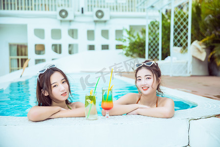 夏天清凉美女白天两个比基尼闺蜜泳池趴着摄影图配图