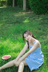 夏季消闲白天美女草地乘凉吃瓜摄影图配图