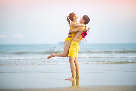 爱情白天一对年轻情侣沙滩拥抱转圈圈摄影图配图