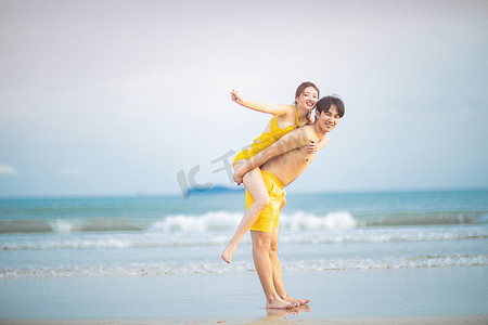 爱情白天一对年轻情侣沙滩背着摄影图配图