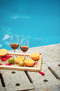 民宿打卡摄影照片_夏天泳池白天放在托盘里的红酒和水果泳池边上无摄影图配图