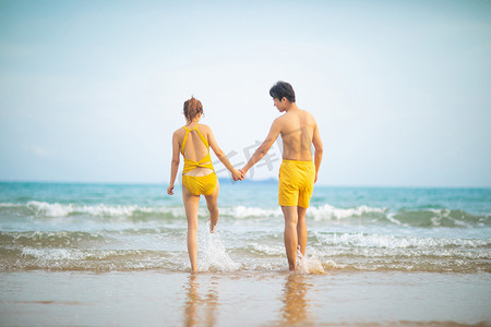 爱情情人节白天一对情侣的背影沙滩手拉手摄影图配图