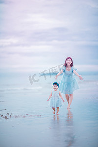 沙滩玩耍摄影照片_亲子关系傍晚年轻的妈妈和女儿沙滩奔跑摄影图配图