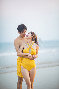 海边情侣摄影照片_爱情白天一对年轻情侣沙滩拥抱对视摄影图配图