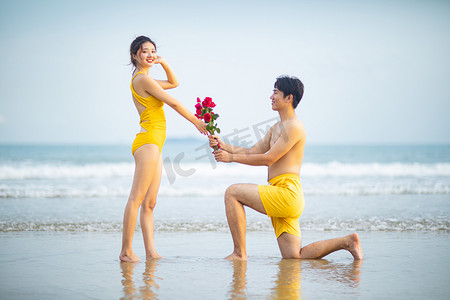 海边情侣摄影照片_爱情白天一对情侣沙滩单膝跪地摄影图配图