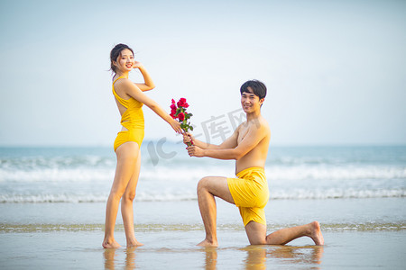爱情情人节求婚白天一对情侣沙滩单膝跪地摄影图配图
