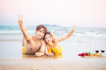 爱情白天一对情侣沙滩趴在地上挥手摄影图配图