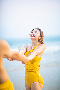 爱情情人节白天恋爱中的女孩沙滩手拉手转圈摄影图配图
