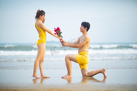 爱情求婚白天求婚的情侣沙滩单膝跪地摄影图配图