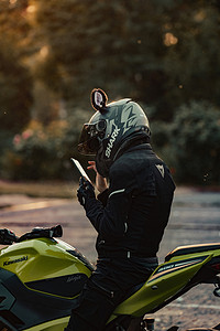 摩托车摄影照片_人物黄昏美女户外刷手机摄影图配图