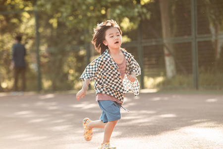 夏日儿童人像白天长发小男孩操场自由奔跑摄影图配图