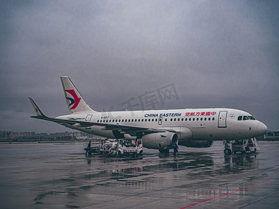 旅游飞机摄影照片_飞机场雨天一架飞机机场上飞前检查摄影图配图