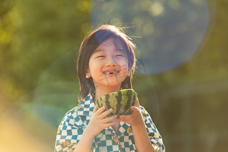 夏日儿童人像白天长发小男孩阳光下开心的吃西瓜摄影图配图