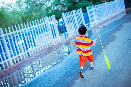 夏日儿童人像雨后小男孩马路上奔跑的背影摄影图配图
