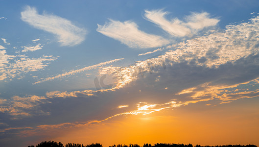 夏天风光夕阳一片片云彩天空太阳透过云彩照射大地摄影图配图