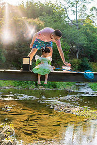 亲子活动摄影照片_女儿的夏天傍晚父女溪边捞鱼摄影图配图