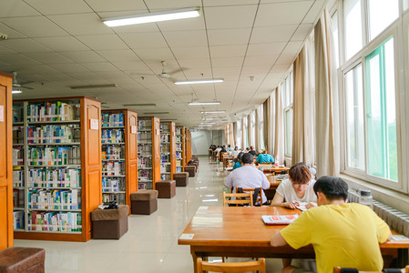 教育书本摄影照片_教育白天书架书桌图书馆学习摄影图配图