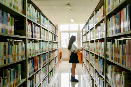 女人物摄影照片_人像白天女孩子书架前看书摄影图配图