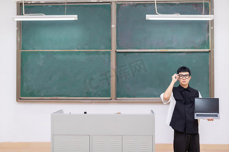 帅气大学生在黑板前用电脑扶眼镜