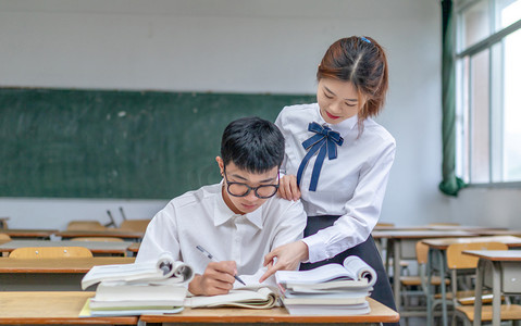 在校园课室里辅导学习的青春男女大学生