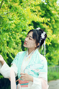 中国风古典花摄影照片_古风古装白天汉服美女室外赏花摄影图配图