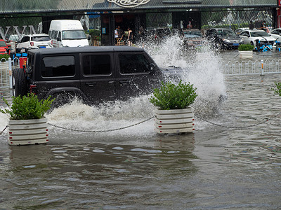 防汛预警摄影照片_被淹的城市白天汽车积水中行驶摄影图配图