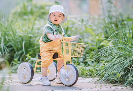 艺术字亲子游摄影照片_儿童白天骑小车的小男孩室外骑车摄影图配图