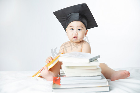 婴儿启蒙教育白天疑惑表情的小男孩室内坐在书堆里摄影图配图