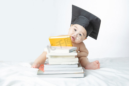 书堆摄影照片_婴儿启蒙教育白天坐在书堆里的男婴儿室内咬书本摄影图配图