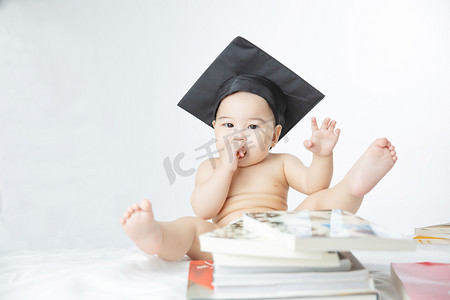 小孩伸手摄影照片_婴儿启蒙教育白天书堆里的可爱男婴室内伸手摄影图配图