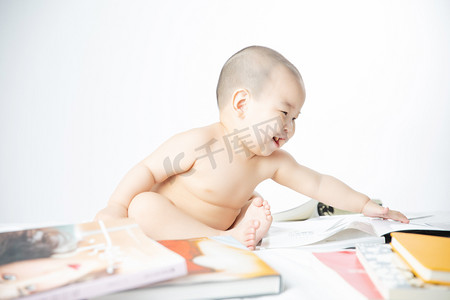 童真摄影照片_婴儿启蒙教育白天书堆里的婴儿室内拿书摄影图配图