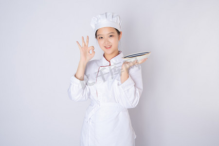 年轻女厨师白天一个女厨师白背景上拿盘手势OK摄影图配图
