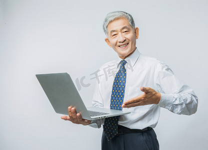 老年人办公白天老年人室内手拿电脑摄影图配图