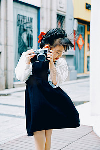 橱窗摄影照片_户外白天拿着相机逛街的小女孩人像摄影图配图